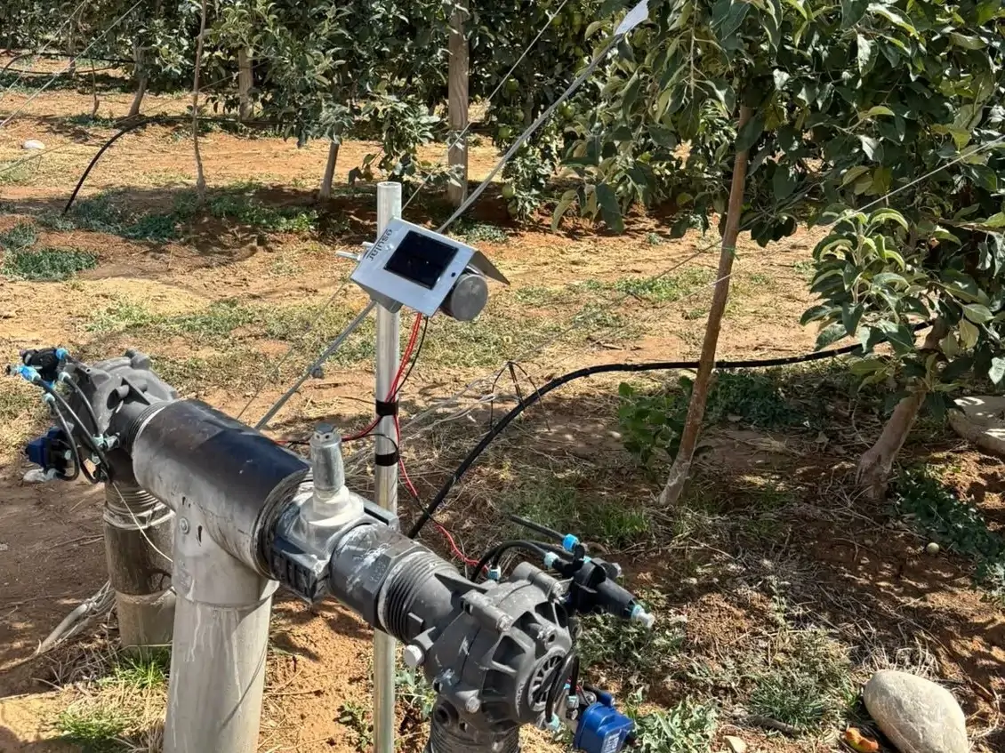 Elma bahçesinde hidrolik vanalı manifold ve direğe takılı Smart-Garden LoRa ünitesi