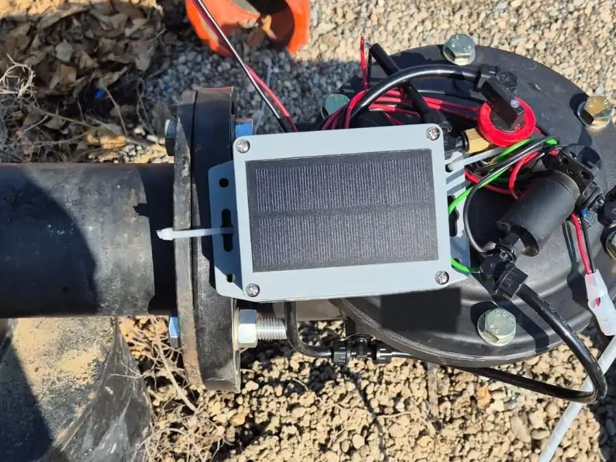 Narenciye bahçesinde hidrolik vananın borusuna kelepçeyle takılı Smart-Garden LoRa ünitesi